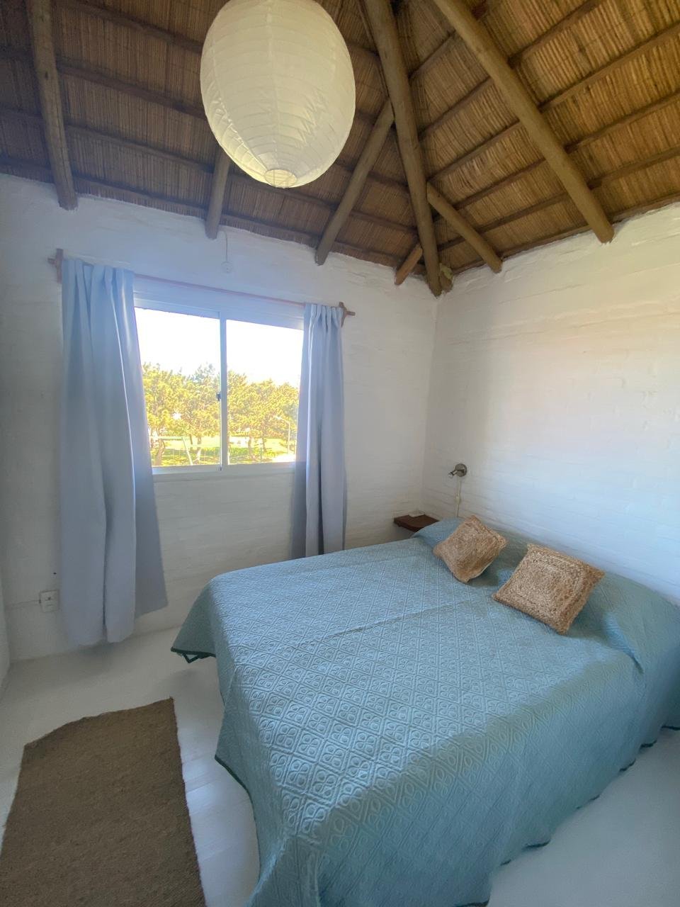 Dormitorio con cama matrimonial, cubrecama celeste y aire acondicionado