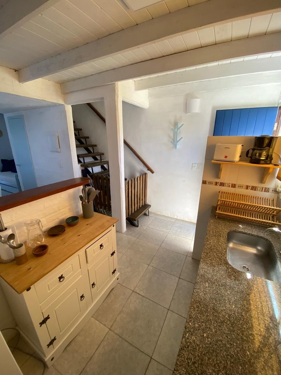 Cocina con barra y escalera de madera al piso superior