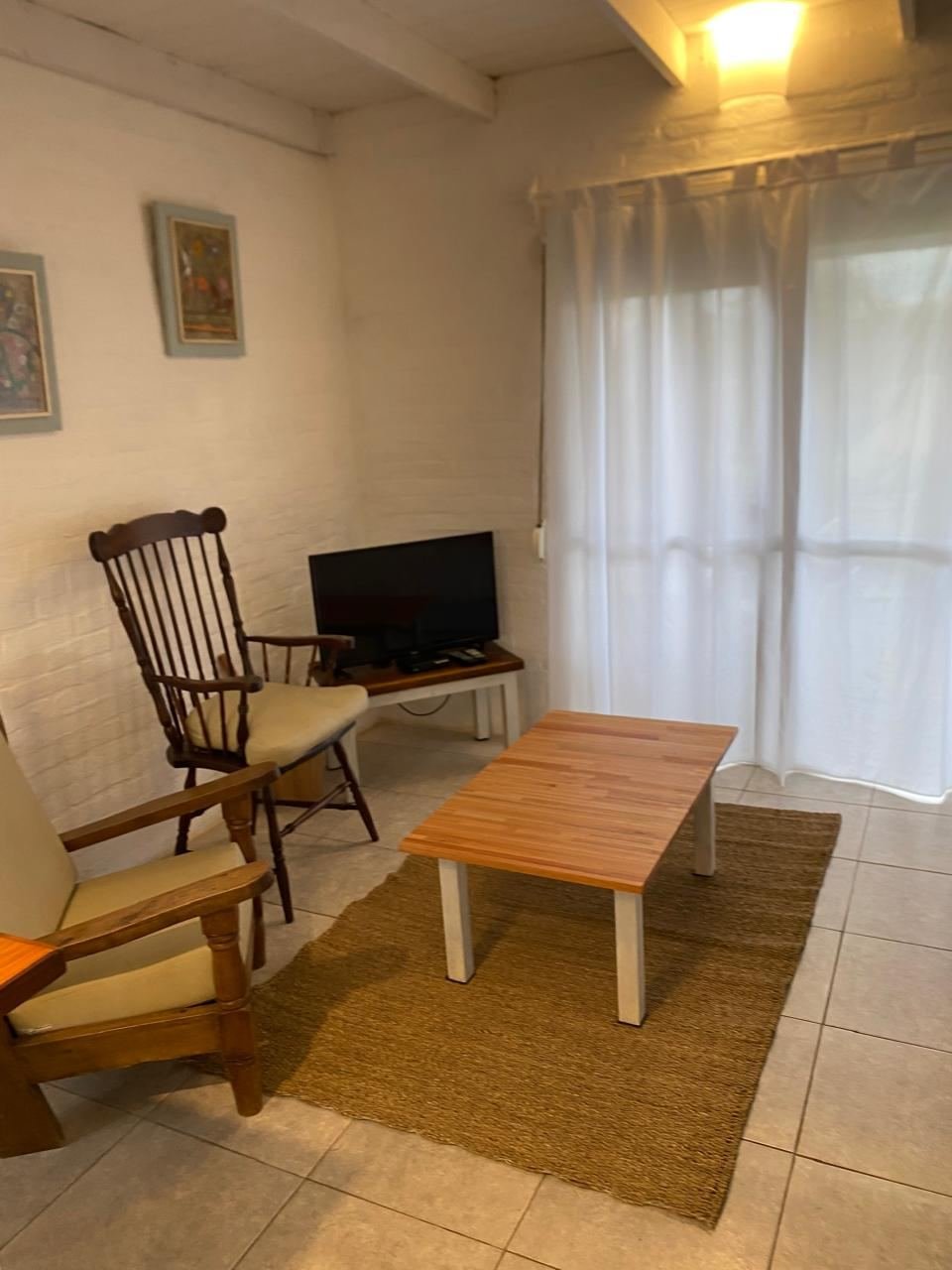 Estar con mecedora, TV y cortinas de lino blanco