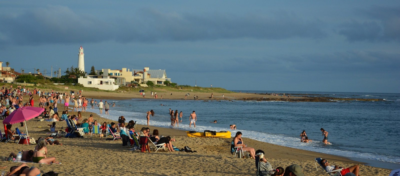 Playa de La Paloma al atardecer, con el faro y las casas sobre la costa